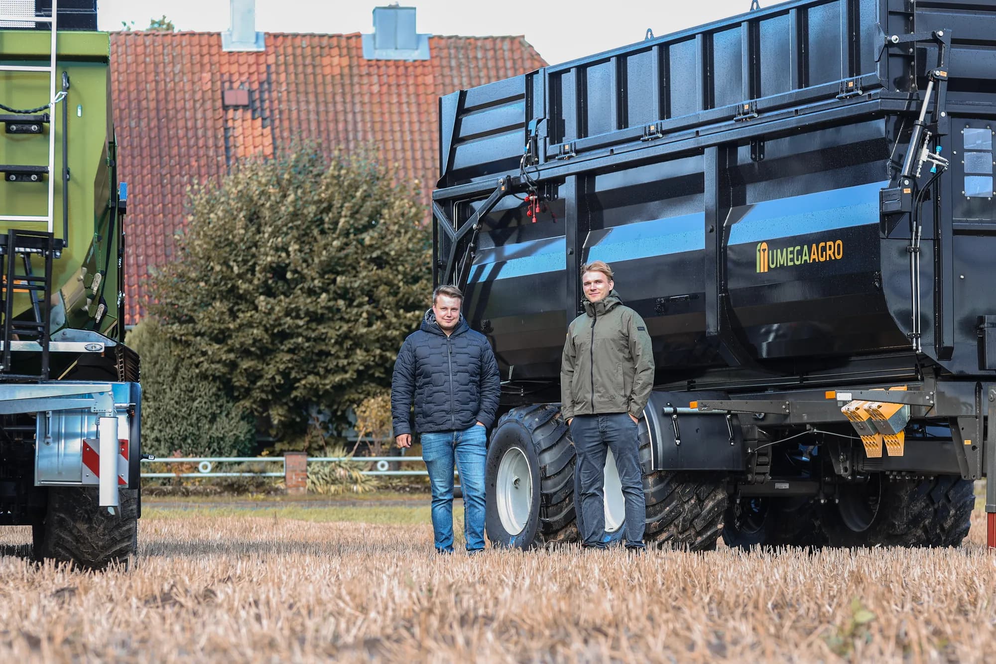 Maximilian Kötter und ein weiterer Mann vor einem Umega-Agro-Anhänger auf dem Feld